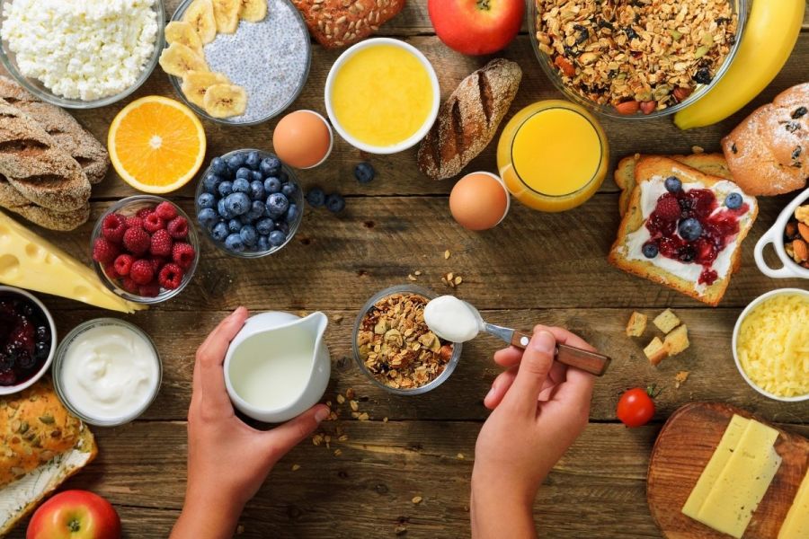 Girl cooking breakfast with granola, yoghurt and fruit.