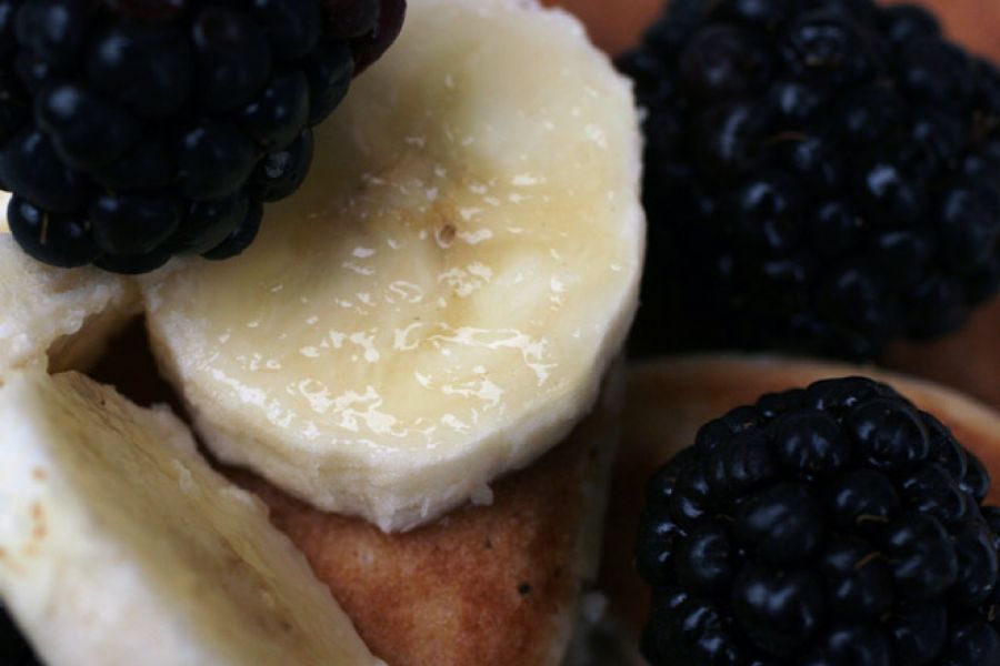 Close up of pancakes garnished with blacberries and banana.