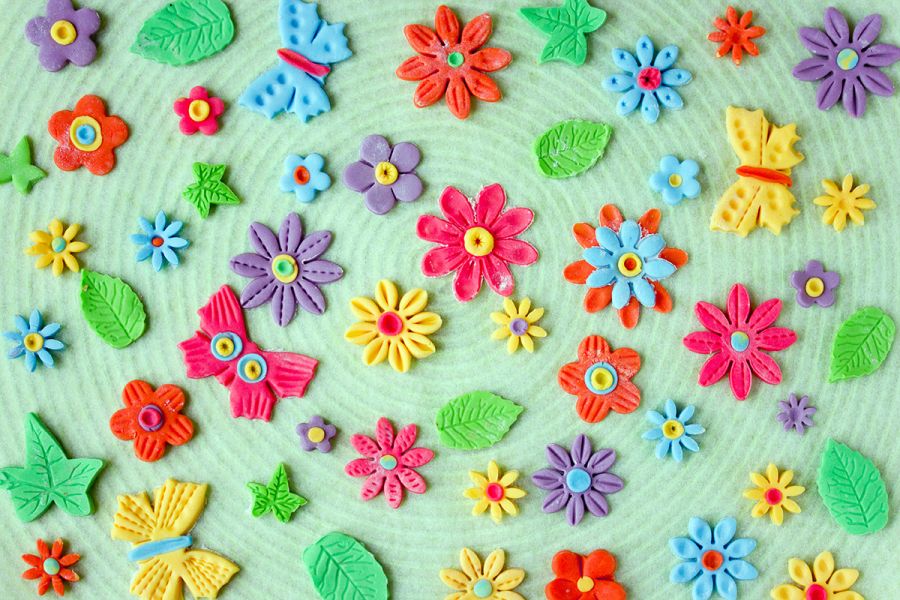 Easter colorful background with edible butterfly, flowers and leaves from sugar paste.
