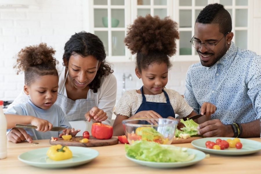 Happy couple enjoying preparing food with their daughters.