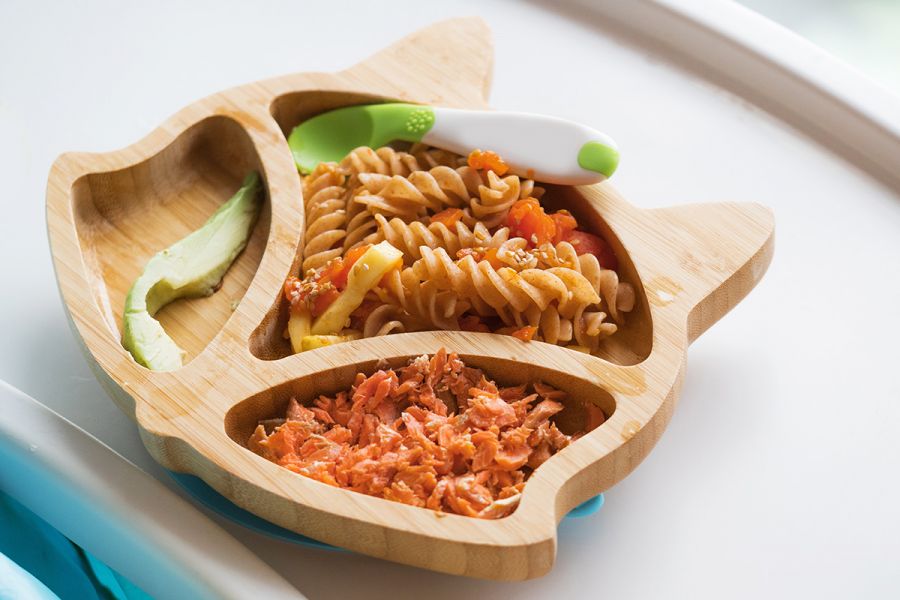 Avocado, fusilli pasta and salmon on a toddlers plate.