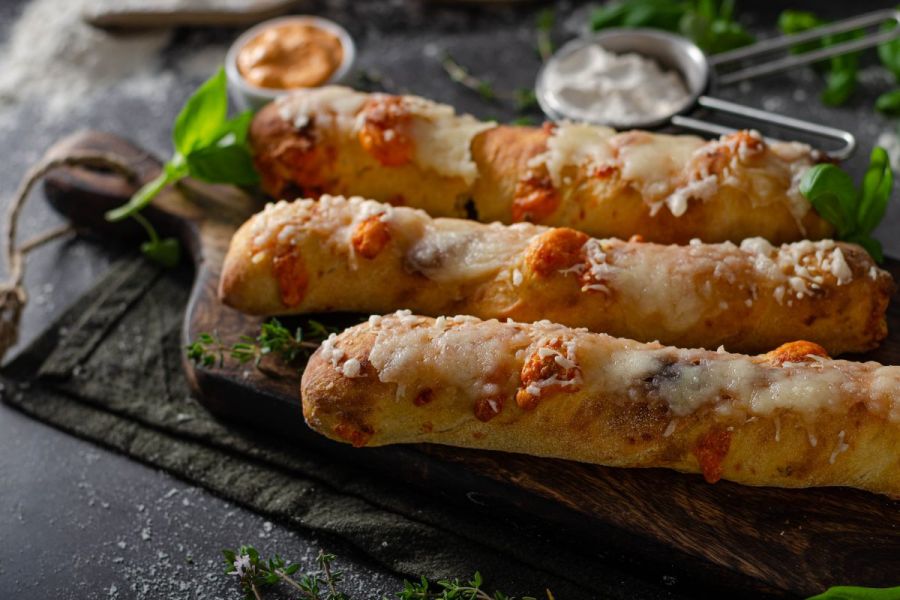 Three cheese dippers on the foreground with dipping sauces on the background.