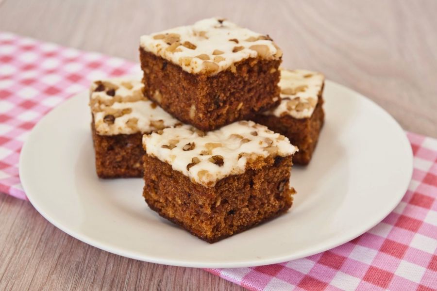 A plate with frosted carrot cake squares.