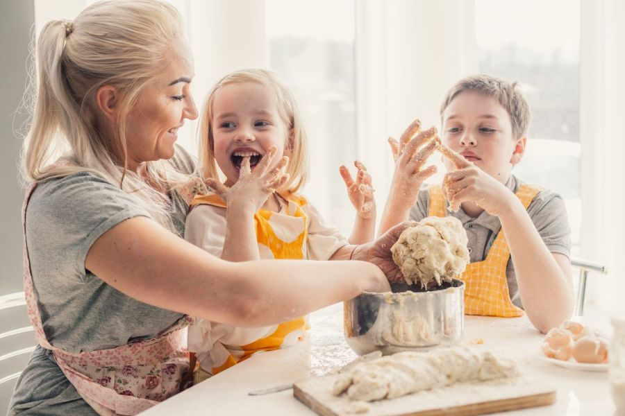 Mom cooking with her kids, boy and girl, preparing dough.
