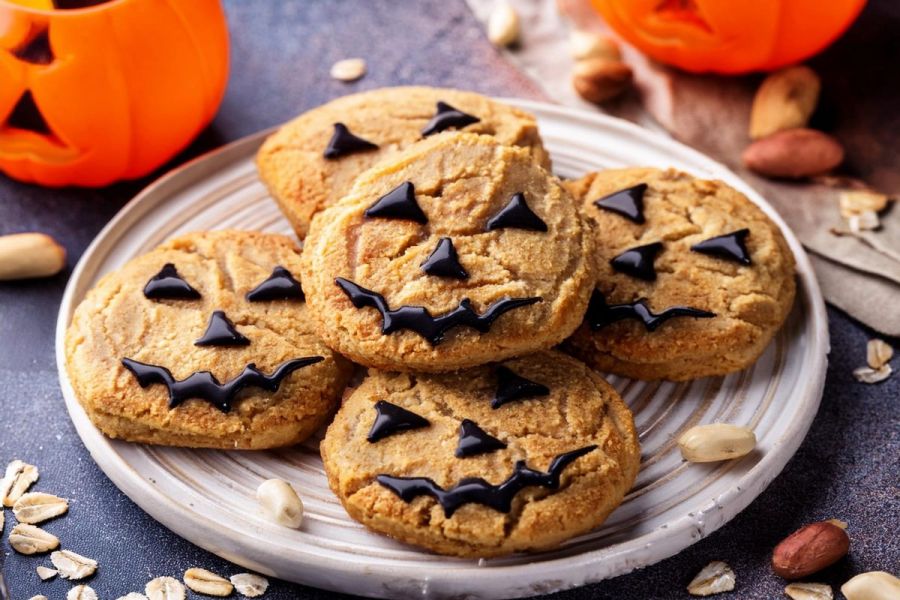 A plate with panut butter and oatmeal cookies with chocolate decorations as scary faces or pumpkin faces.